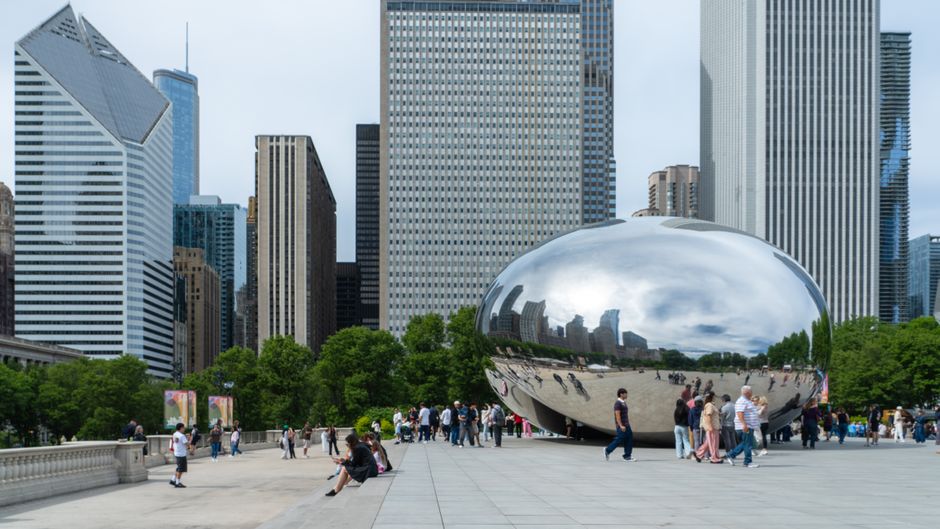 Capture of Cloud Gate with Chicago skyscrapers in background, iconic city sculpture.