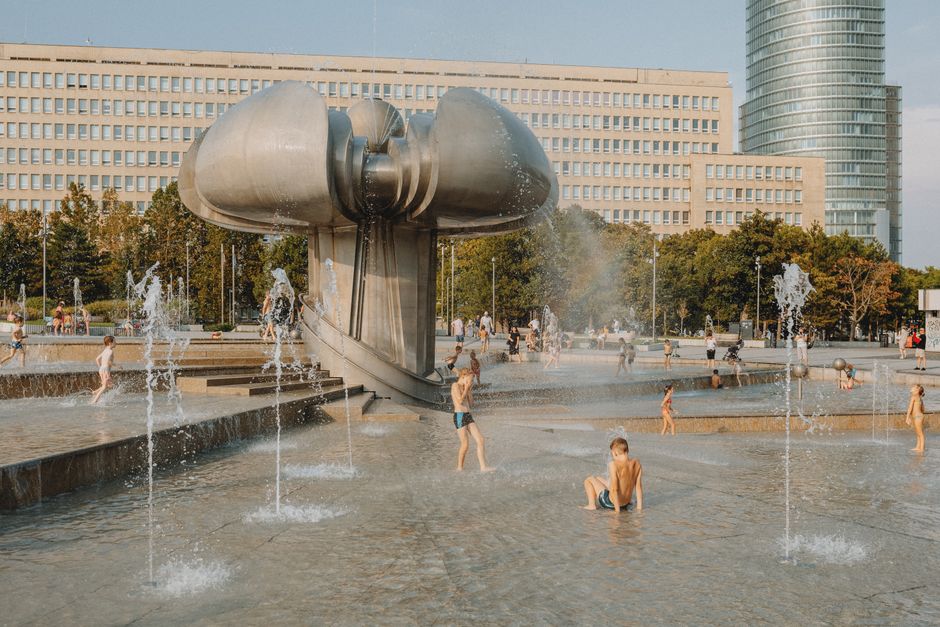 Children enjoying a playful day at a modern urban fountain under the summer sun.