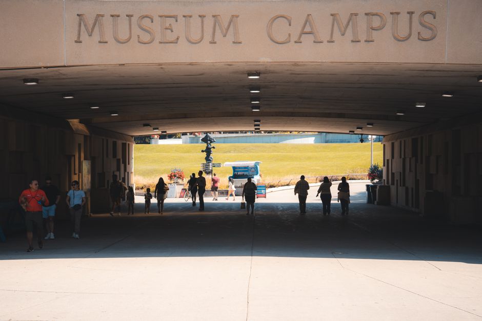 Silhouette of visitors walking through a tunnel at Museum Campus, leading outdoors.
